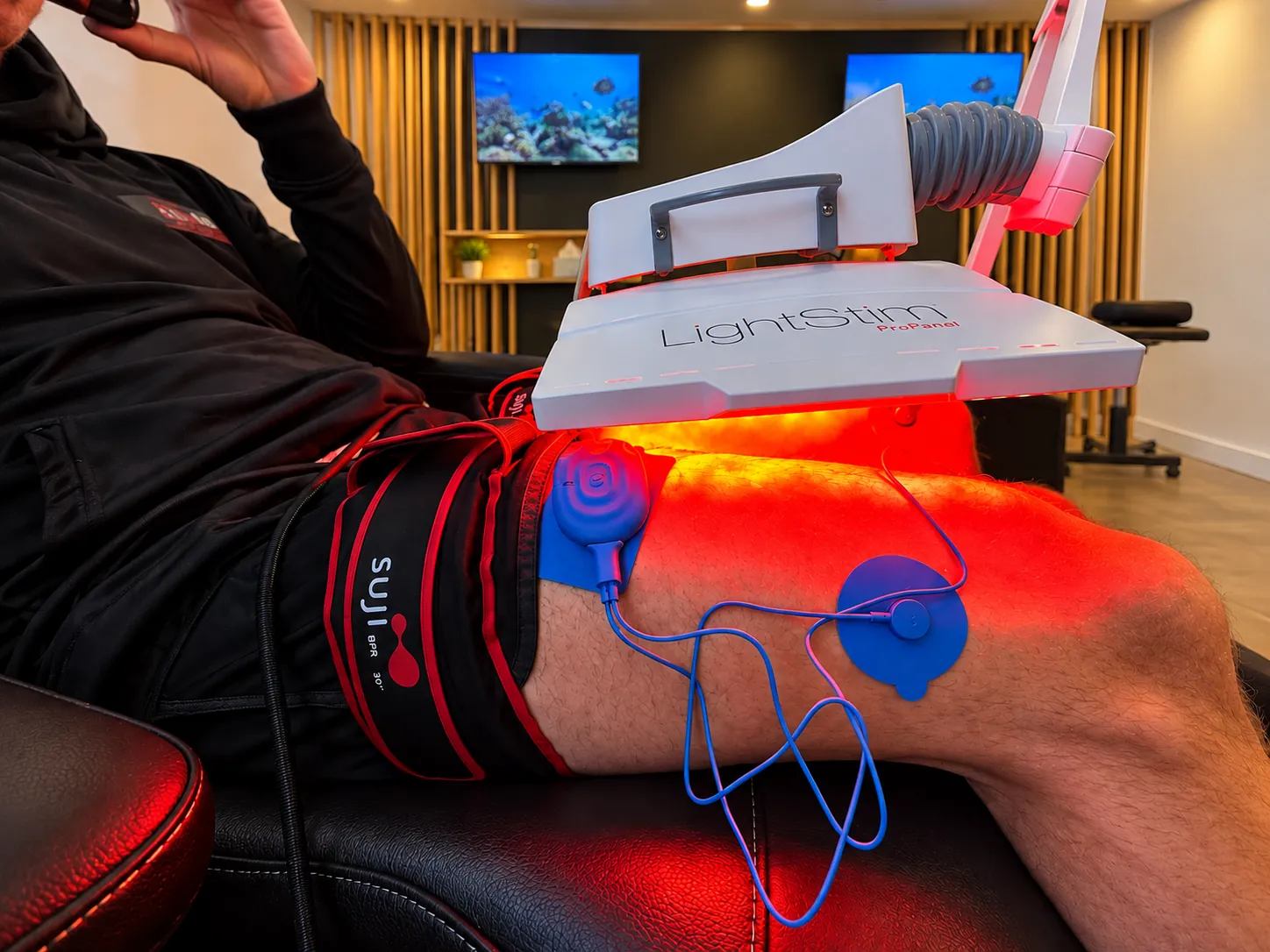 Red light, blood flow restriction cuffs and muscle stimulation used together on a client’s thigh